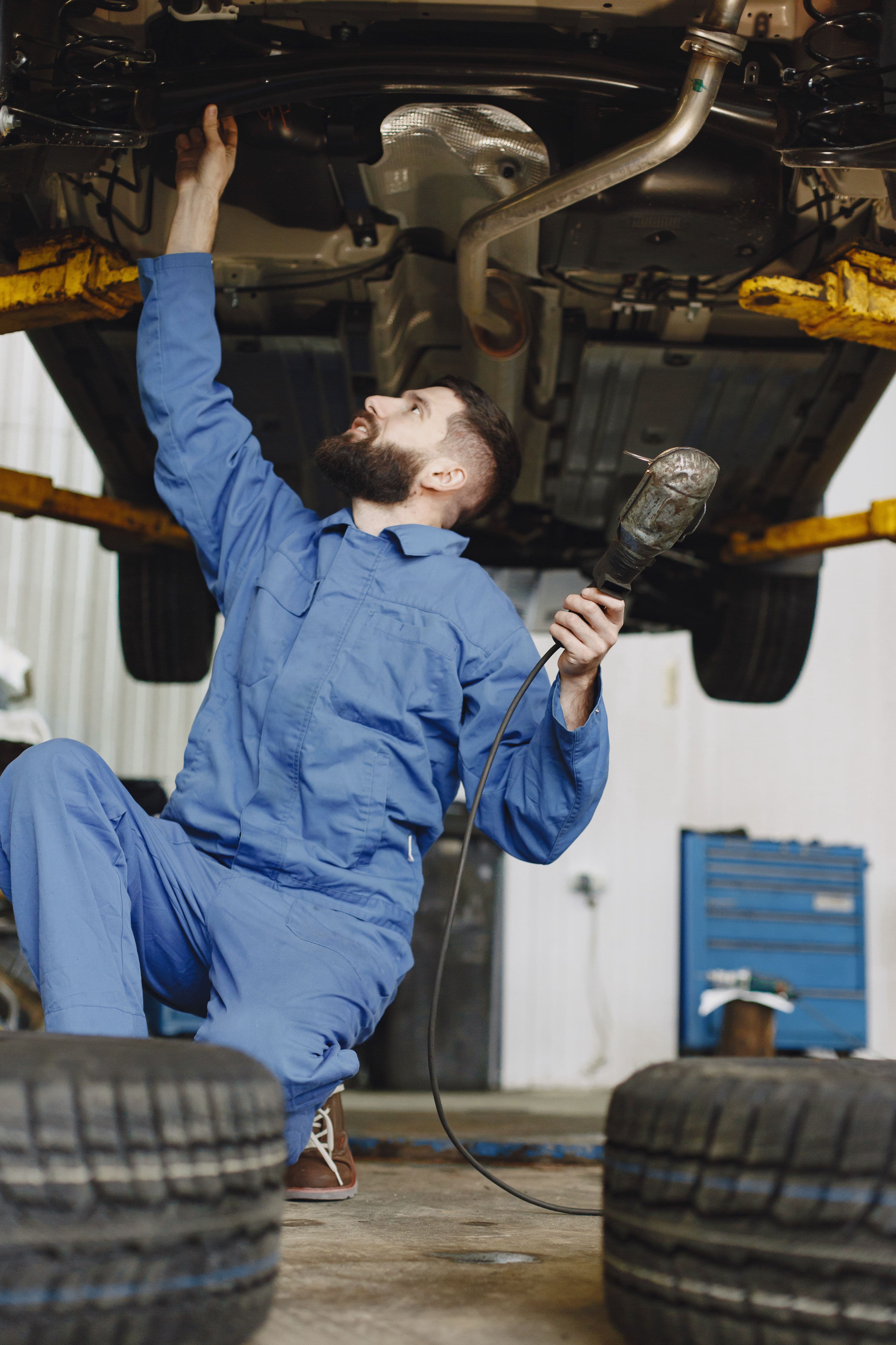 Mechanik pracující pod vozem zvednutým na hydraulickém zvedáku
